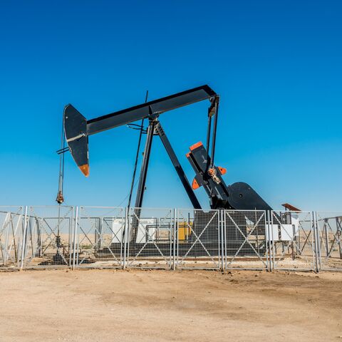 Nodding donkey rig pumping crude oil up from the ground of an oil field in the desert.