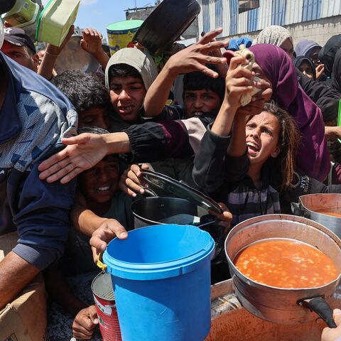 Displaced Palestinians scuffle for a portion of hot food at a charity kitchen at the Nuseirat refugee camp in the central Gaza Strip on May 5, 2025.