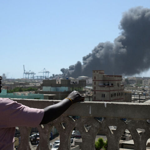 A man watches as smoke billows after a drone strike on the port of Port Sudan on May 6, 2025. Drones struck the airport and targeted an army base in Port Sudan on May 6, officials said, the third straight day the Sudanese army-aligned government's seat of power has come under attack. (Photo by AFP) (Photo by -/AFP via Getty Images)