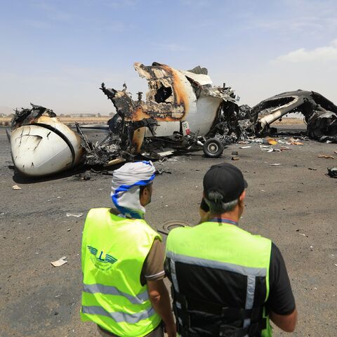Airport employees stand next to a destroyed plane at the Sanaa International Airport on May 7, 2025, a day after Israel's military warplanes struck Yemen's rebel-held capital Sanaa.