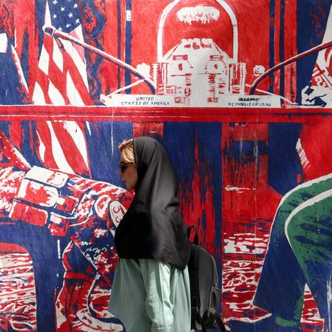 A woman walks past an anti-US mural near the former US Embassy in Tehran, on May 11, 2025.