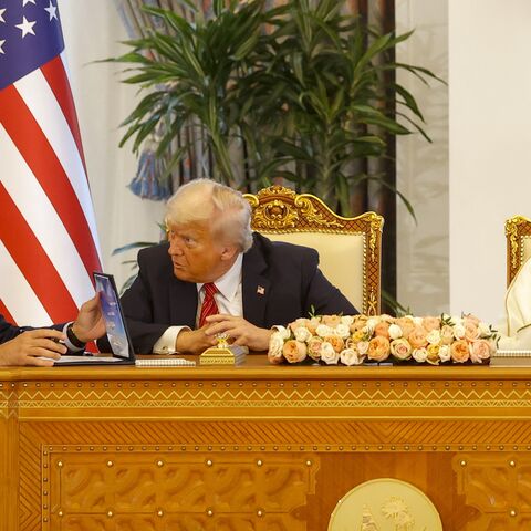 Qatar's Emir Sheikh Tamim bin Hamad Al Thani (R) sits next to US President Donald Trump as he speaks to Boeing CEO Kelly Ortberg (L).