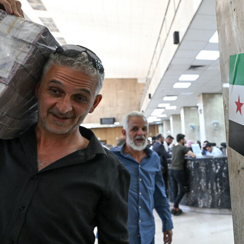 A man carrying a stash of Syrian pounds, leaves the central bank in Damascus on May 21, 2025.