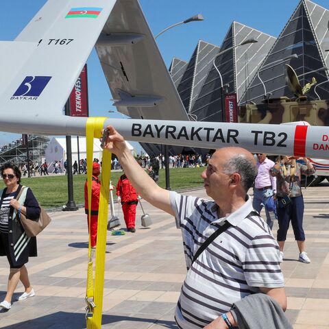 A man poses next to the Bayraktar TB2 drone, manufactured by Turkey's Baykar, as it is presented during the opening of the aerospace and technology festival 'Teknofest Azerbaijan' at Baku Crystal Hall in Baku, on May 27, 2022.