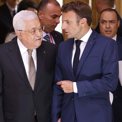 French President Emmanuel Macron (R) speaks with Palestinian President Mahmoud Abbas as they make their way to a meeting at the Elysee Presidential Palace in Paris on July 20, 2022.