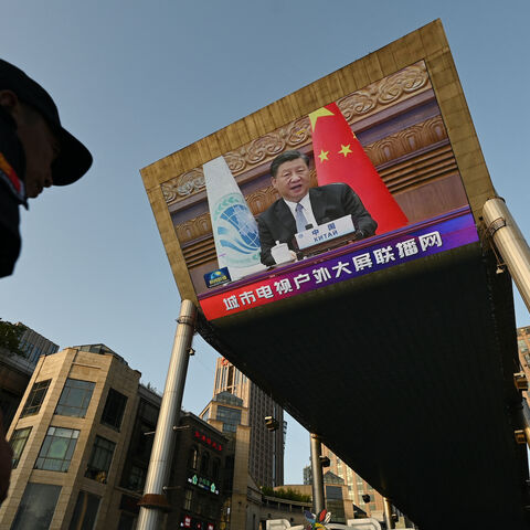 A security guard stands below a giant screen showing news footage of China's President Xi Jinping speaking virtually to the Shanghai Cooperation Organization meeting, which was being held in India, at a shopping mall in Beijing on July 4, 2023.