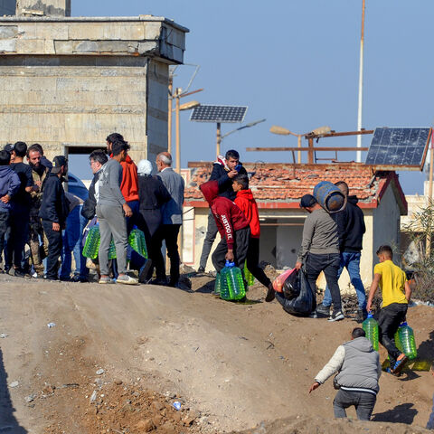 A photo taken from the Lebanese side of the northern border crossing of al-Arida shows Syrian rebel fighters assisting with the passage of Syrians back into their country, Dec. 10, 2024.