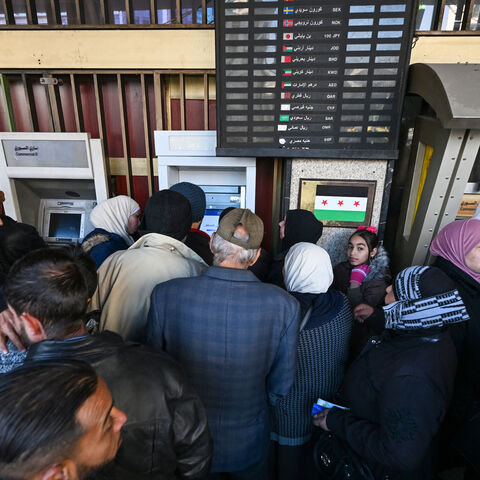 People queue to use ATM machines outside a bank in Damascus on Dec. 16, 2024.