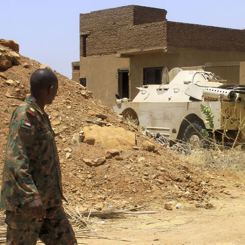 A Sudanese army officer walks near an armoured vehicle seized after their capture of a base used by the rival Rapid Support Forces (RSF) paramilitaries after the latter group evacuated from the Salha area of Omdurman, the twin-city of Sudan's capital, on May 26, 2025. Sudan, Africa's third largest country, has been ravaged by more than two years of war between the army and the RSF. The conflict has killed tens of thousands of people, displaced 13 million and created what the United Nations describes as the
