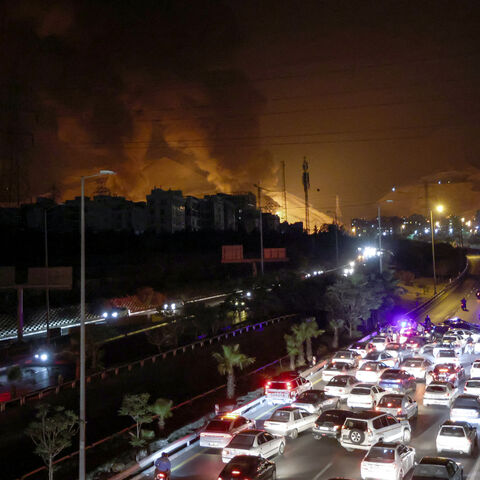 TOPSHOT - Vehicles jam a highway as a fire blazes nearby in the oil depots of Shahran, northwest of Tehran, on June 15, 2025. Israel and Iran exchanged fire on June 14, a day after Israel unleashed an unprecedented aerial bombing campaign that Iran said hit its nuclear facilities, "martyred" top commanders and killed dozens of civilians. (Photo by ATTA KENARE / AFP) (Photo by ATTA KENARE/AFP via Getty Images)