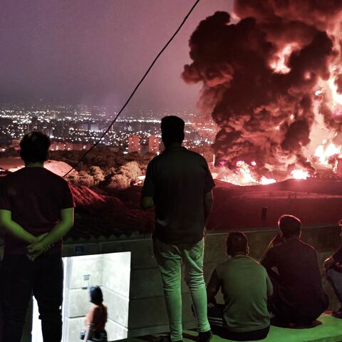 TEHRAN, IRAN - JUNE 15: People observe fire and smoke from an Israeli attack on the Shahran oil depot on June 15, 2025 in Tehran, Iran. Iran's foreign minister said the country would respond "decisively and proportionally" to a wave of attacks that Israel launched beginning in the early hours of June 13. The attacks targeted multiple military, scientific and residential locations, as well as senior government officials. (Photo by Stringer/Getty Images)