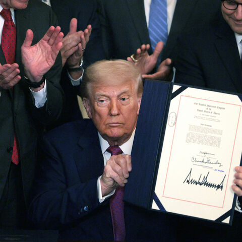 President Donald Trump, joined by Sen. John Barrasso (R-WY), Speaker of the House Mike Johnson (R-LA) and other lawmakers, holds up an executive order after signing a series of bills related to California’s vehicle emissions standards during an event in the East Room of the White House on June 12, 2025 in Washington, DC.