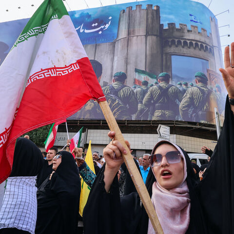 An Iranian woman lifts a national flag during a rally protesting the US attack on Iran in Enghelab Square in Tehran on June 22, 2025.