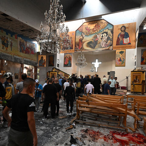 People and rescuers inspect the damage at the site of a reported suicide attack at the Saint Elias church in Damascus' Dweila area on June 22, 2025.