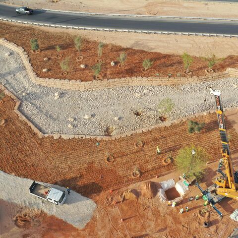 An aerial picture shows workers using a crane to plant trees in a park project by the roadside in the Saudi capital Riyadh, on March 29, 2021. - Although the OPEC kingpin seems an unlikely champion of clean energy, the "Saudi Green Initiative" aims to reduce emissions by generating half of its energy from renewables by 2030. (Photo by - / AFP) (Photo by -/AFP via Getty Images)