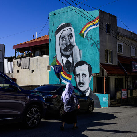 A woman walks past a mural depicting Lebanese Druze politician Walid Jumblatt (bottom, R) and Syrian Druze nationalist leader Sultan al-Atrash, in the predominantly Druze city of Beit Jann on November 16, 2023. Around 150,000 Druze, Arab adherents of an esoteric offshoot of Shiite Islam, live in Israel. Most identify as Israelis and the men -- not women -- are conscripted into the military, many serving in combat units. The Druze community is concentrated in 16 villages in northern Israel, among them Beit J
