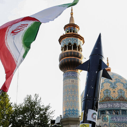 Iranians lift up a flag and the mock up of a missile during a celebration following Iran's missiles and drones attack on Israel, on April 15 2024, at Palestine square in central Tehran. Iran launched the attack on April 14, its first ever to directly target Israeli territory, in retaliation for a deadly air strike widely blamed on Israel that destroyed Tehran's consular building in Syria's capital early this month. (Photo by ATTA KENARE / AFP) (Photo by ATTA KENARE/AFP via Getty Images)