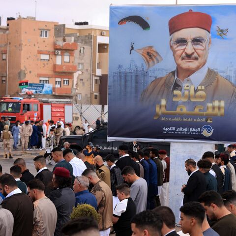 Security forces stand guard as Libyans perform the morning prayer of Eid al-Fitr with a portrait of the military strongman of eastern Libya, Khalifa Hiftar, in the background in the port city of Benghazi on March 31, 2025.