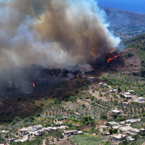 An aerial view shows smoke billowing from a forest fire in the coastal Syrian province of Latakia on July 5, 2025. Syrian emergency workers were battling forest fires raging in the coastal province of Latakia on Saturday for a third day in tough conditions as neighbouring Turkey sent assistance. Syria's ministry for emergencies and disaster management said teams from Turkey began helping on Saturday morning "as part of regional coordination to face the fires", with the assistance including two aircrafts and