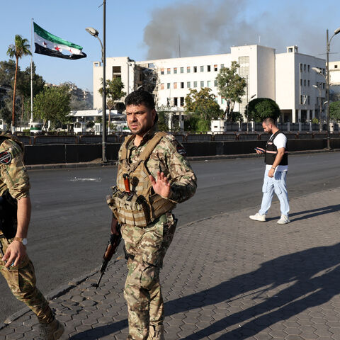 Syrian security forces stand guard in front of the heavily damaged Syrian army and defense ministry headquarters complex in Damascus, following Israeli strikes on July 16, 2025.