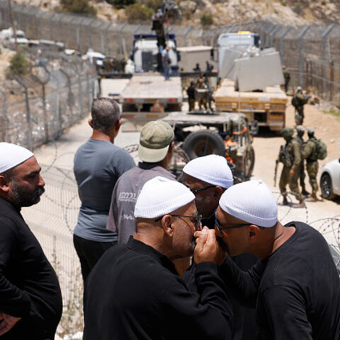 Druze men greet each other as they wait near the border fence in the town of Majdal Shams, in the Israeli-annexed Golan Heights, as Syrian Druze who had crossed over the day before to the village, cross back to return to Syrian, on July 17, 2025. Syrian government forces have withdrawn from the whole of Sweida province after days of sectarian bloodshed in the heartland of the Druze minority, a war monitor and witnesses said July 17, 2025. (Photo by Jalaa MAREY / AFP) (Photo