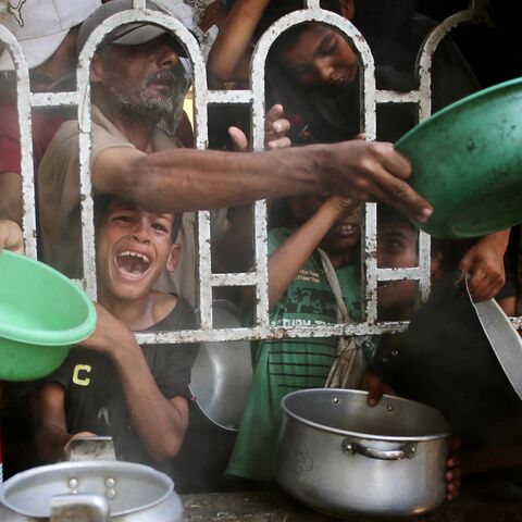 Palestinians shove to receive a hot meal at a charity kitchen in the Mawasi area of Khan Yunis in the southern Gaza Strip on July 22, 2025.