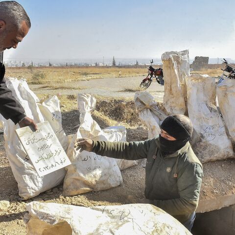 Workers package human remains recovered from the mass grave in Damascus, Syria, on Dec. 17, 2024.