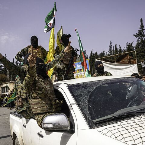 SDF fighters wave flags and flash victory signs from a vehicle during a convoy procession in Aleppo, Syria, on April 9, 2025. 