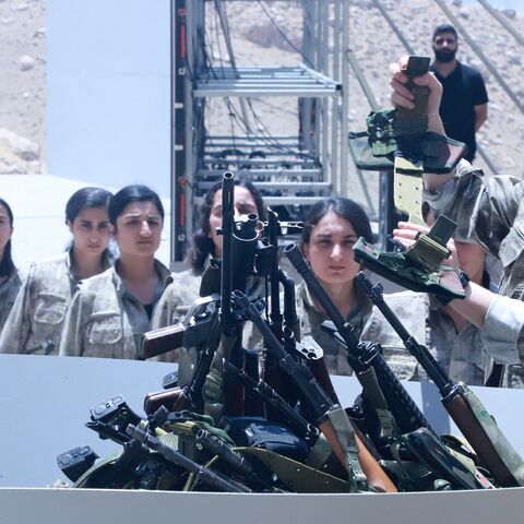 Fighters with the Kurdistan Workers Party (PKK) line up to put their weapons into a pit during a ceremony in Sulaimaniyah, in Iraq's autonomous Kurdistan region, on July 11, 2025.