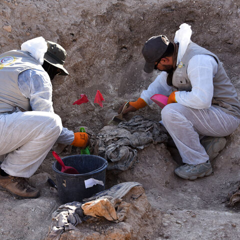 Workers dig out human remains at the Khasfa site near the northern Iraqi city of Mosul, where authorities have begun excavating a mass grave believed to contain thousands of victims of the Islamic State (IS) on Aug. 17, 2025.
