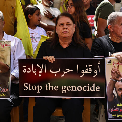 Fadwa, wife of leading member of the Palestinian Fatah party Marwan Barghouti, the most high-profile Palestinian detainee in Israeli custody, lifts a placard during a rally to support him in Ramallah city in the occupied West Bank, attended by politician Mustapha Barghouti (L) and political activist Omar Assaf on August 19, 2025. The UN's human rights office on Ausust 19 condemned Israel's far-right national security minister Itamar Ben Gvir for taunting Barghouti, who has spent more than 20 years behind ba