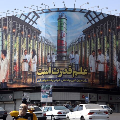 Iranians drive next to a billboard displaying pictures of nuclear scientists, centrifuges and a sentence reading in Farsi " Science is the power," at the Enqelab Square in Tehran, on Aug. 29, 2025.