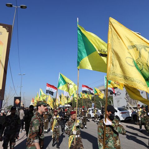 Fighters lift flags of Iraq and paramilitary groups, including al-Nujaba and Kataib Hezbollah, during a funeral in Baghdad for five militants killed a day earlier in a US strike in northern Iraq, on Dec. 4, 2023.