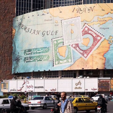 People walk and drive past a billboard depicting as postage stamps the disputed Abu Musa and Greater and Lesser Tunb islands in Tehran on Oct. 26, 2024.