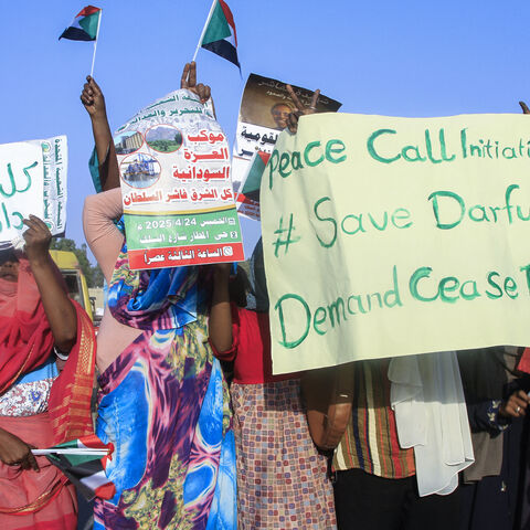People lift national flags and placards during a rally called for by Sudan's Popular Front for Liberation and Justice in Port Sudan on April 24, 2025, to denounce the siege imposed by the paramilitary Rapid Support Forces (RSF) on El-Fasher city and express support for its residents. 
