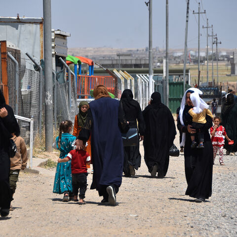 Women and children walk at the Al-Amal Camp (formerly Al-Jadaa), south of Mosul in northern Iraq, which houses Iraqi families who have been repatriated from Syria's Al-Hol camp, on May 8, 2025.
