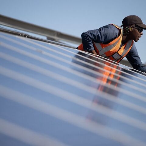A worker fits solar panels onto frames during construction at South Africa's first municipally owned solar plant, during International World Environment Day, on June 5, 2025, in Atlantis near Cape Town.