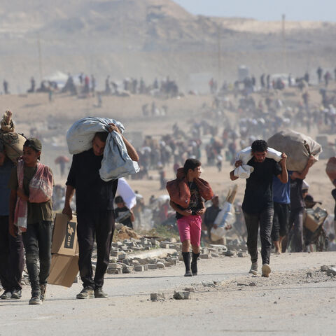 Palestinians walk with bags of humanitarian aid they received at a distribution centre run by the US and Israeli-backed Gaza Humanitarian Foundation (GHF), at the so-called "Netzarim corridor", in Nuseirat in the central Gaza Strip, on Sept. 26, 2025.