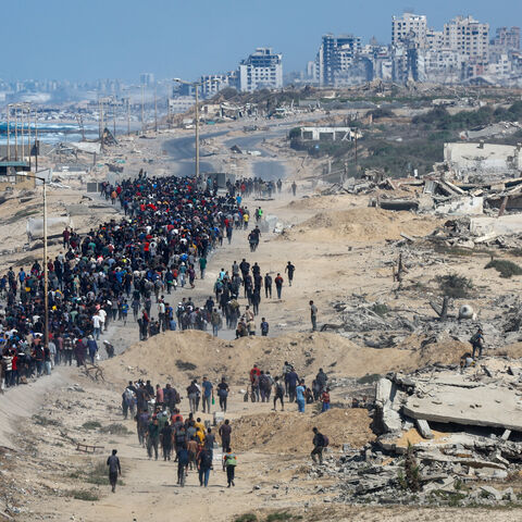 Palestinians, who were displaced to the southern part of Gaza at Israel's order during the war, walk along a road ast destroyed buildings as they attempt to return to the north after a ceasefire between Israel and Hamas in Gaza went into effect, in the central Gaza Strip, October 10, 2025. REUTERS/Mahmoud Issa