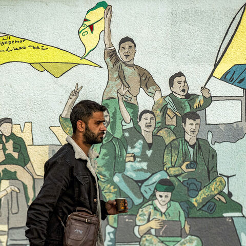 A man walks past a mural depicting supporters of the Syrian Democratic Forces (SDF), one of them raising a flag showing the face of Abdullah Ocalan — founding member of the militant Kurdistan Workers' Party (PKK) outlawed by Turkey, in Syria's northeastern city of Qamishli on Dec. 16, 2024.