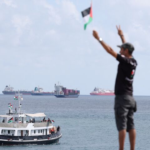 An activist waves the Palestinian flag as a boat carrying Swedish climate activist Greta Thunberg and activists.