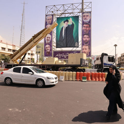 A woman walks past a deactivated Kheibar Shekan ballistic missile in front of a picture of Iran's Supreme Leader Ayatollah Ali Khamenei in Tehran's Bahrestan Square on Sept. 27, 2025, as part of an exhibit to mark the "Sacred Defense Week" commemorating the 1980-88 Iran-Iraq war. 