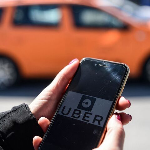 A woman opens the UBER application on her mobile phone at the Eminonu district on March 30, 2018 in Istanbul. 