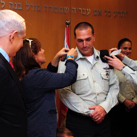 In this handout by the Israeli Government Press Office, Prime Minister Benjamin Netanyahu (L) looks on as military chief of staff Lt.-Gen. Benny Gantz (R) adjusts the epaulettes of Brig. Gen. Eyal Zamir for his swearing in as military secretary, Tel Aviv, Nov. 26, 2012.