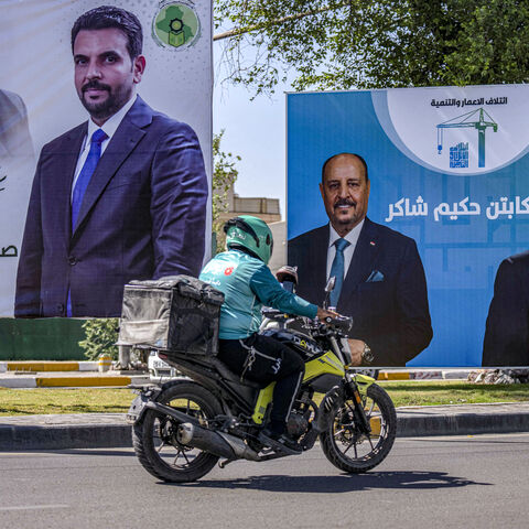 A delivery person rides a motorcycle past election billboards for candidates and blocs competing in Iraq's upcoming November parliamentary election, including incumbent Prime Minister Mohammed Shia al-Sudani, displayed along a street in Baghdad on Oct. 3, 2025. 