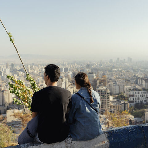 A couple sits facing the skyline of Tehran from Bam-e Tehran in Tehran, Iran on October 24, 2025. (Photo by Bahram / Middle East Images via AFP) (Photo by BAHRAM/Middle East Images/AFP via Getty Images)