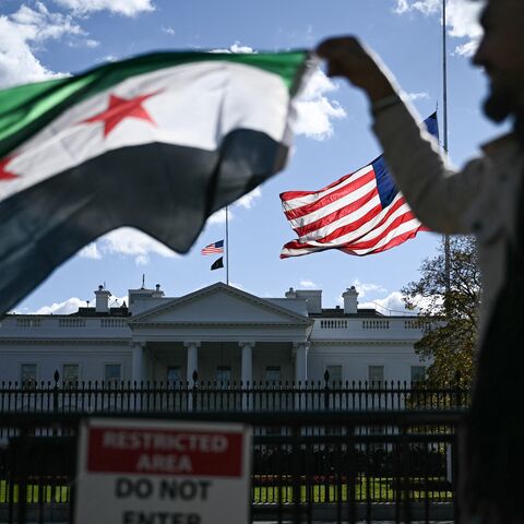 A man holds a Syrian flag across the street from the White House after Syrian President Ahmed al-Sharaa met with US President Donald Trump at White House in Washington on Nov. 10, 2025. 