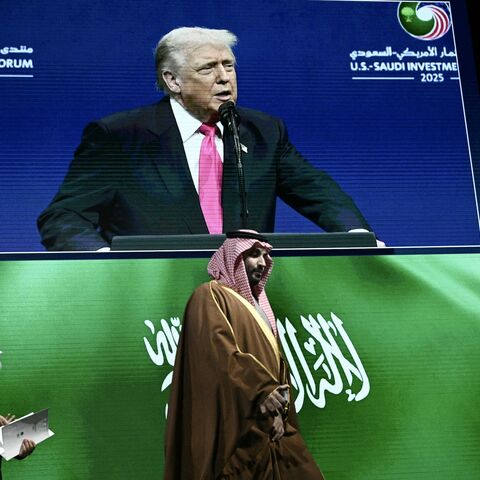 Crown Prince and Prime Minister of the Kingdom of Saudi Arabia Mohammed bin Salman (R) arrives as US President Donald Trump is seen on a screen.
