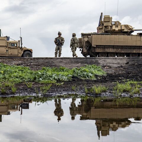 US Army soldiers stand near armored military vehicles on the outskirts of Rumaylan in Syria's northeastern Hasakah province, bordering Turkey, on March 27, 2023.