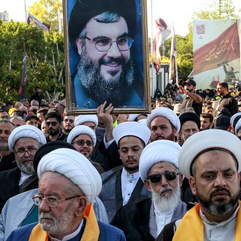 A Shiite Muslim cleric holds a picture of Hassan Nasrallah.